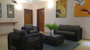 Un salón con muebles de mimbre, una mesa de centro con una planta y un cuadro en la pared.