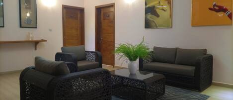 A living room with wicker furniture, a coffee table with a plant, and a painting on the wall.