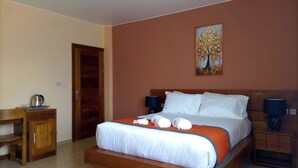 Un dormitorio con cama, mesitas de noche, un escritorio de madera y una puerta.