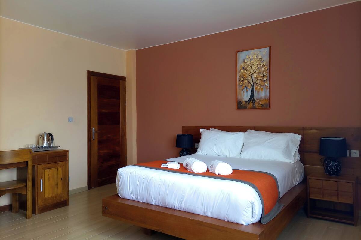 A bedroom with a bed, bedside tables, a wooden desk, and a door.