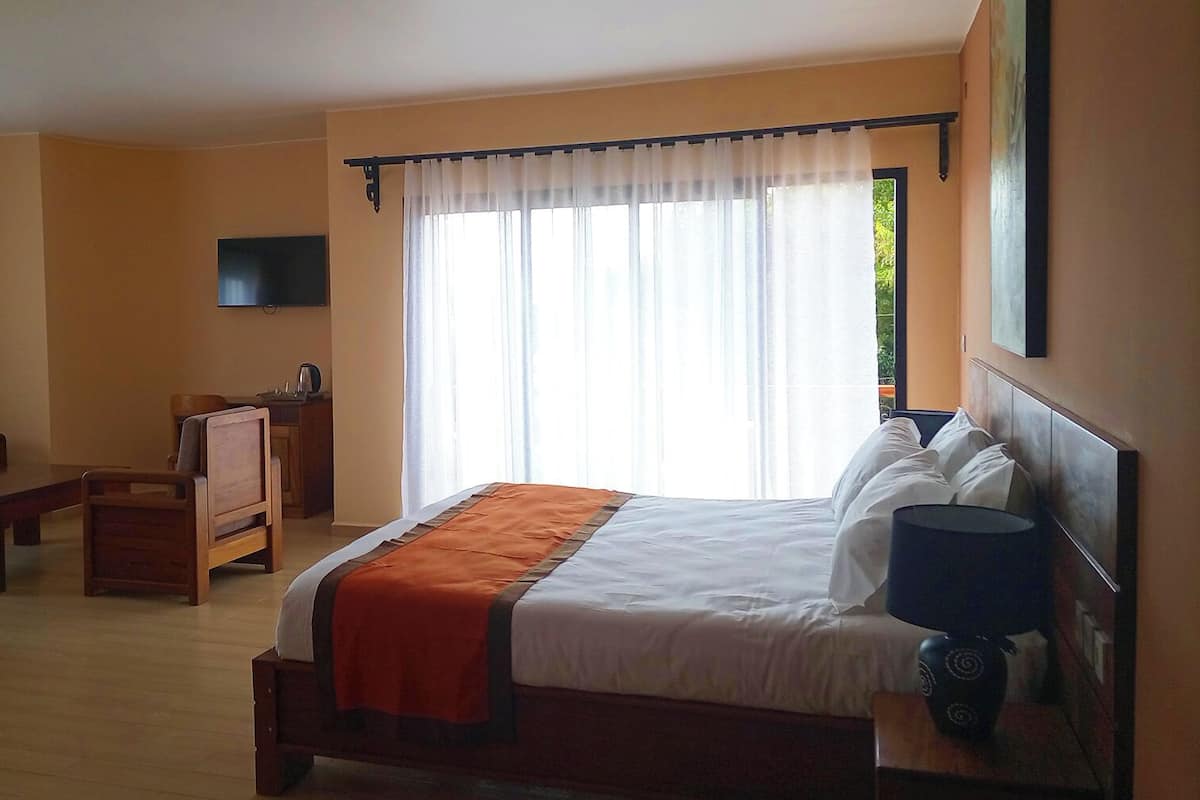 A hotel room with a bed, a TV, a desk, and a chair.