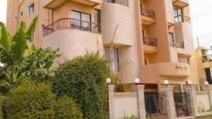 Un edificio de varios pisos con balcones, una columna central y una entrada con portón.