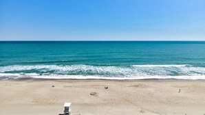A beach with a lifeguard tower, sandy beach, and ocean. - Charming 1-bedroom oceanfront condo in Carolina Beach, perfect for 4 guests! (Carolina Beach)