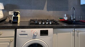 Cucina con lavatrice, fornello e pensili.