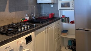 Una cucina con piano cottura a gas, lavatrice, forno a microonde e scaldabagno.