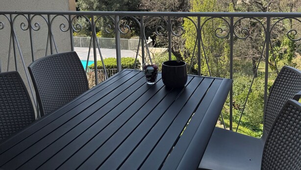 Un balcone con tavolo, sedie e una pianta in vaso.