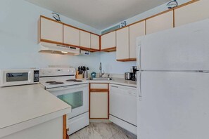Eine kleine Küche mit Mikrowelle, Herd, Spüle und Kühlschrank.