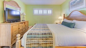 A bedroom with a bed, a television on a wooden dresser, and a window with blinds. - Stunning 1 Bedroom Oceanfront Condo in Carolina Beach 1106 (Carolina Beach)