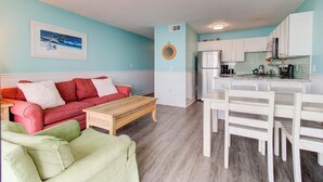 A compact living space with a kitchenette, a red sofa, a green armchair, and a dining table. - Stunning 1 Bedroom Oceanfront Condo in Carolina Beach 1106 (Carolina Beach)