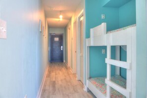 A hallway with bunk beds, a door, and a light fixture. - Experience oceanfront luxury at 1108 Ocean Serenity, Carolina Beach. (Carolina Beach)