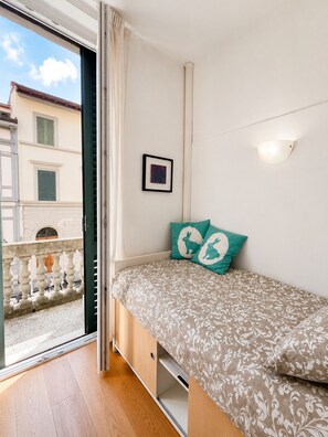 A bedroom with a bed, a small wall-mounted light, a framed picture, and a balcony with a railing. - Elegant Florence Apartment with Private Terrace (Firenze)