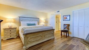 A bedroom with a bed, nightstands, a chair, and a wardrobe. - Stunning oceanfront 2-bedroom condo at Carolina Beach 1110 (Carolina Beach)