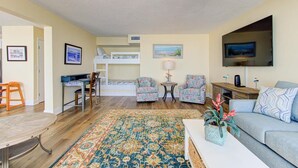 A living room with a bunk bed, a TV, a coffee table, and a patterned rug. - Stunning oceanfront 2-bedroom condo at Carolina Beach 1110 (Carolina Beach)