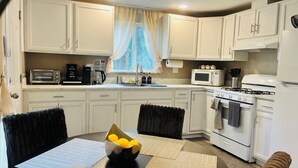 A compact kitchen with white cabinets, a stove, microwave, and a toaster. - Dafna, Unit 3 - Two bedroom/1 Bath stylish home (Cromberg)