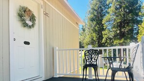 A wooden deck with two black metal chairs, a white door with a wreath, and a sign indicating 'Unit 3'. - Dafna, Unit 3 - Two bedroom/1 Bath stylish home (Cromberg)