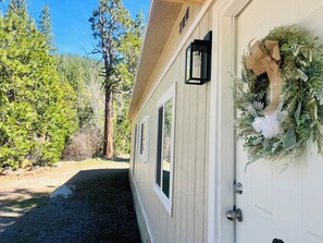 A wooden building with a door adorned with greenery and a light fixture.