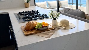 Une cuisine moderne dotée d’un grand îlot central, d’une cuisinière à gaz et offrant une vue sur l’océan.