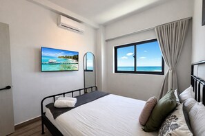 Ein Hotelzimmer mit Bett, Fernseher, Fenster mit Meerblick und Klimaanlage.
