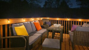 Una terrazza esterna con mobili in vimini, tra cui un divano e delle poltrone, e un tavolino.