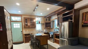 A spacious kitchen with wooden cabinets, a dining area with a table and chairs, a gray sofa, and a refrigerator. - Beautifully Chic, Spacious, WiFi, Near Pullman Yds (Atlanta)