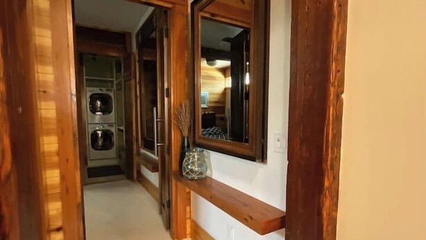 A hallway with wooden beams, a large mirror, and a view into a room with a washing machine. - Beautifully Chic, Spacious, WiFi, Near Pullman Yds (Atlanta)