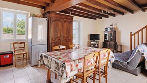 A kitchen with wooden beams, a refrigerator, dining table, chairs, and a television.
