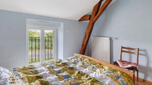 A bedroom with a bed, a chair, a window, and a radiator.