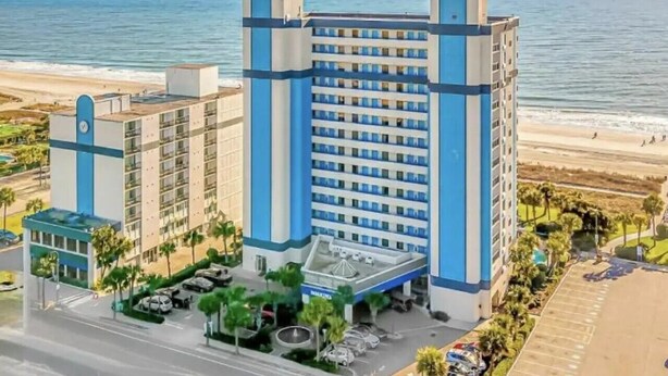 Un hôtel de grande hauteur, avec de nombreux étages, une cour intérieure et une vue sur la plage.