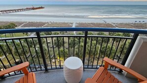 Un balcon avec vue sur l’océan, une jetée et une plage.