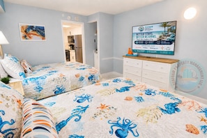 A bedroom with a bed, a dresser, a television, and a wall with a poster. - Modern Oceanfront 1br Condo Boardwalk Beach Resort (Myrtle Beach)