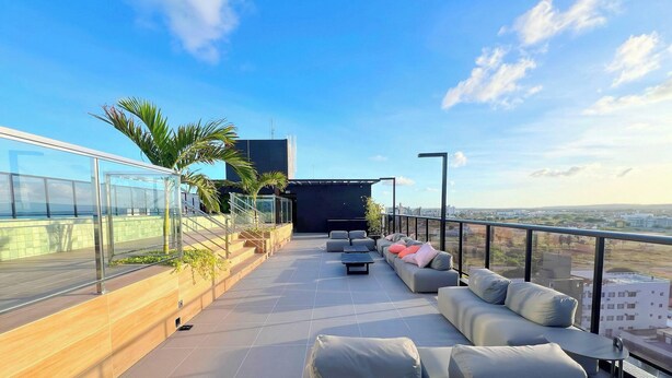 Une terrasse sur le toit, dotée d’un espace extérieur aménagé, d’une rambarde en verre et offrant une vue sur le paysage urbain.