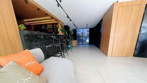 Un intérieur moderne avec un canapé, un coin bar et une vue à travers une porte vitrée.