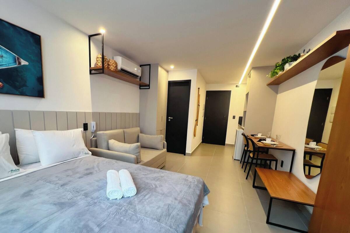 A hotel room with a bed, a sofa, a desk, and a dining table.