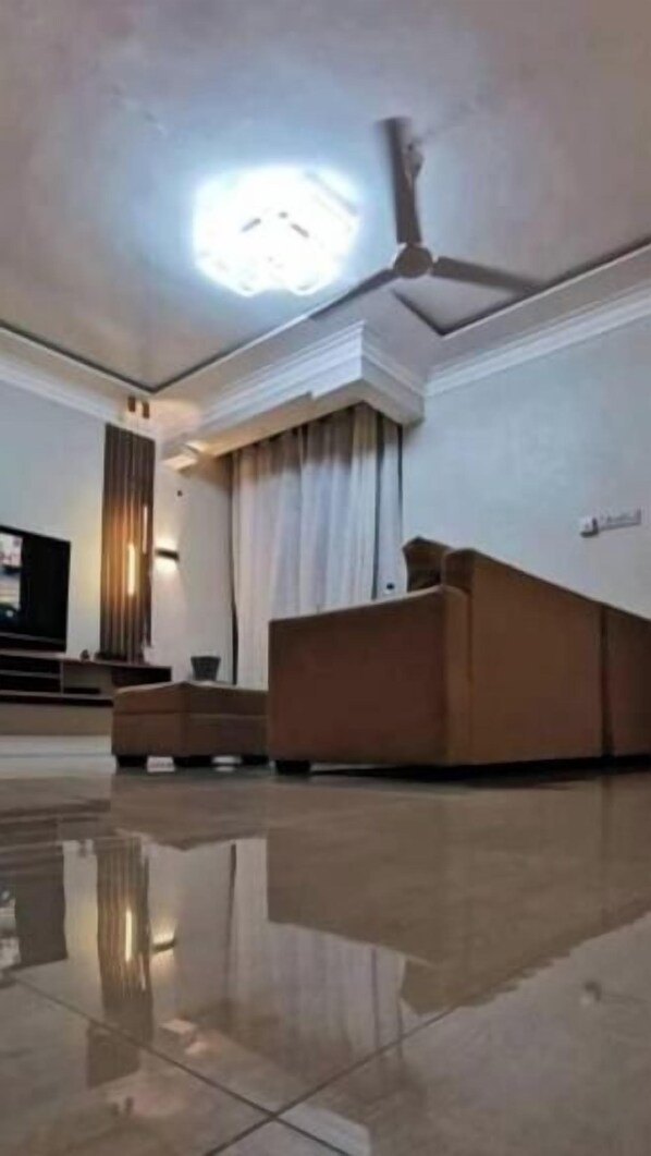 A hotel lobby with a reception desk, a ceiling fan, and a large light fixture. - Legacy Homes 2A Apartment (Dar es Salaam)