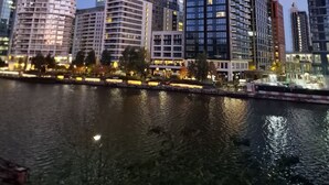 A cityscape with modern high-rise buildings, a river in the foreground, and a clear sky. - Riverthames View Canary Wharf Apartment (London)
