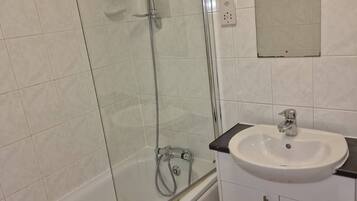 A bathroom with a glass-enclosed shower, a bathtub, a sink, and a mirror.
