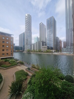 A modern urban landscape with high-rise buildings, a river, and well-maintained greenery. - Riverthames View Canary Wharf Apartment (London)