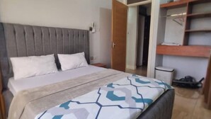 Un dormitorio con cama, armario y puerta abierta que da a otra habitación.