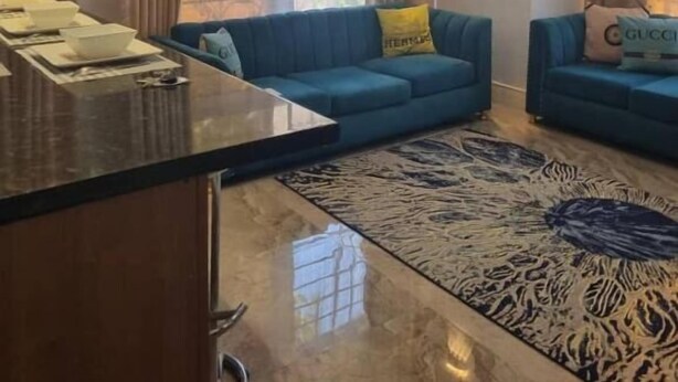 Un soggiorno moderno con un divano blu, un tavolino da caffè e un tappeto decorato.