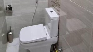 Un bagno moderno e piccolo, con un WC, una doccia e un lavandino a muro.