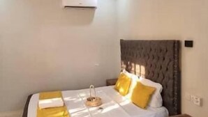 Una camera da letto con un letto, una ventola a soffitto, un condizionatore d'aria e un comodino.