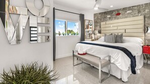 A modern bedroom with a bed, bedside table, and a large mirror. - Sunview Escape, a Freshly Remodeled Retreat! (Palm Springs)