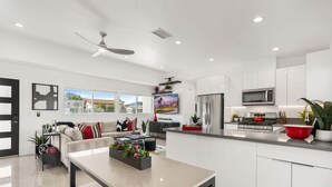 A modern kitchen with white cabinets, a stainless steel refrigerator, a microwave, and a red bowl on the counter. - Sunview Escape, a Freshly Remodeled Retreat! (Palm Springs)