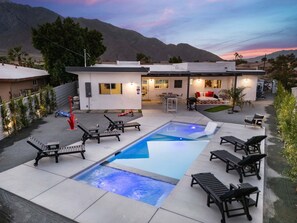 Ein moderner Poolbereich im Freien mit Liegestühlen, einem Whirlpool und einer Terrasse mit Blick auf die Berge.