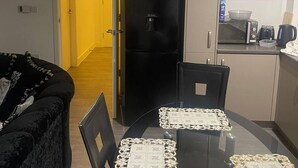 Un espai vital compacte amb taula de dinar, cadires, nevera negra, microones i petita cuina.