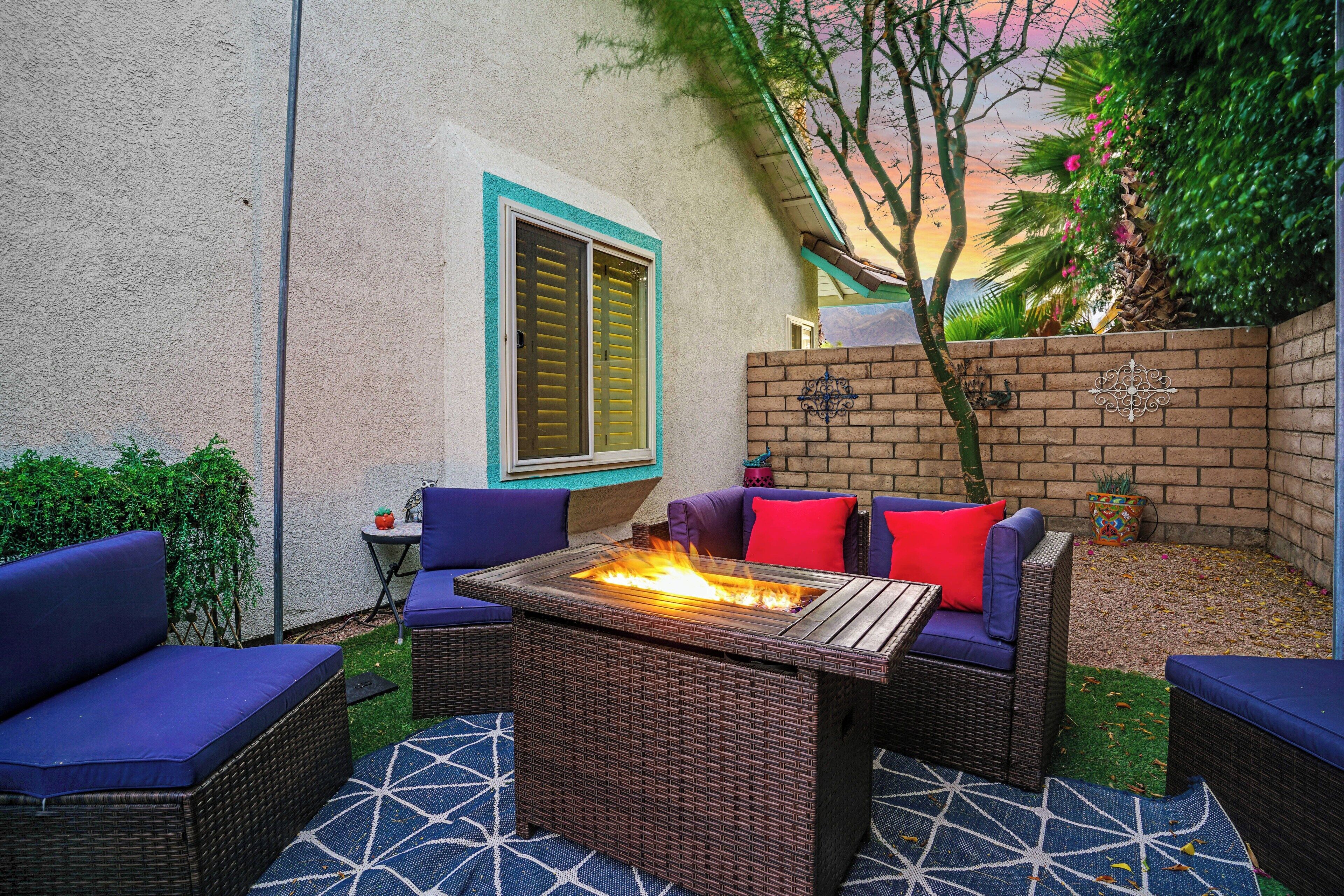 A patio with wicker furniture, a fire feature, and a brick wall.