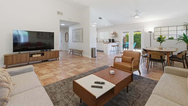 A spacious living room with a flat-screen TV, a coffee table, sofas, and a dining area with chairs and a table. - Welcome to Casa Cielo Vista, a Bright South Palm Springs Retreat! (Palm Springs)