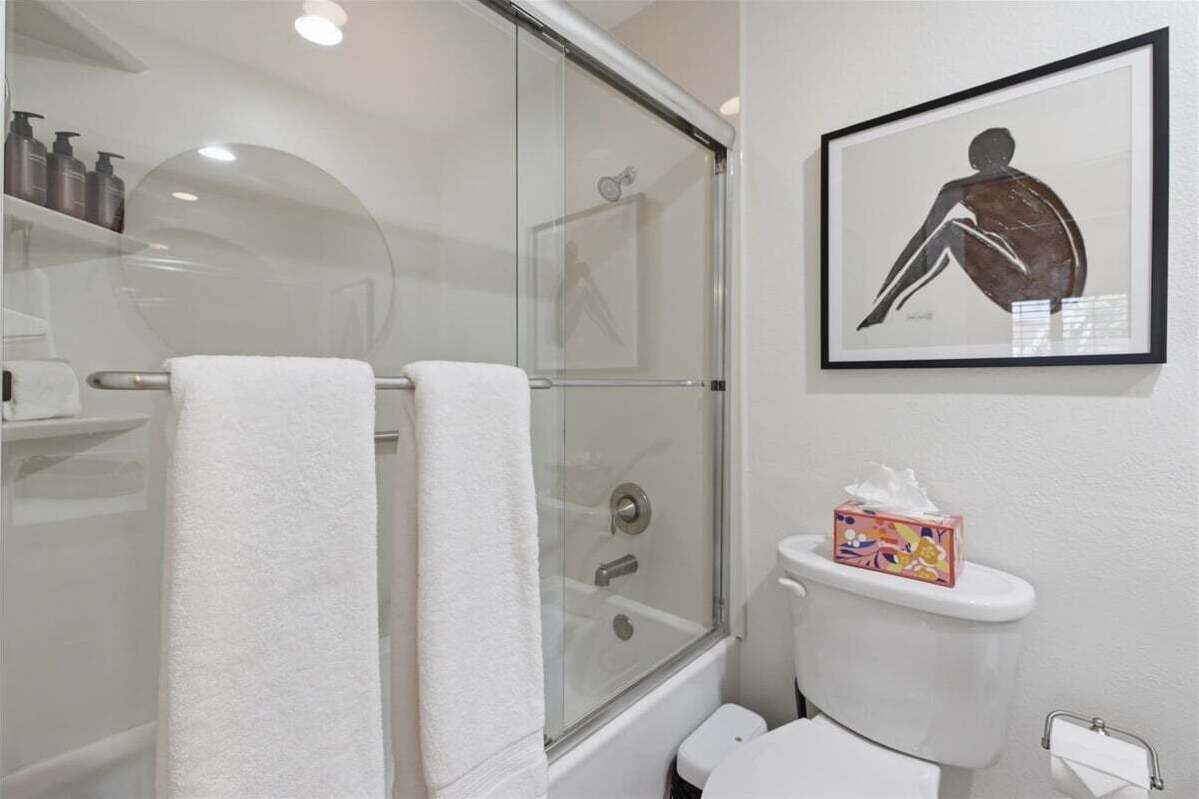 Ein Badezimmer mit einer Duschkabine, einer Toilette und einem gerahmten Kunstwerk an der Wand.