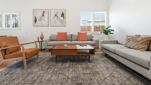 A living room with a sofa, armchair, coffee table, and two abstract paintings on the wall. - Welcome to Casa Cielo Vista, a Bright South Palm Springs Retreat! (Palm Springs)