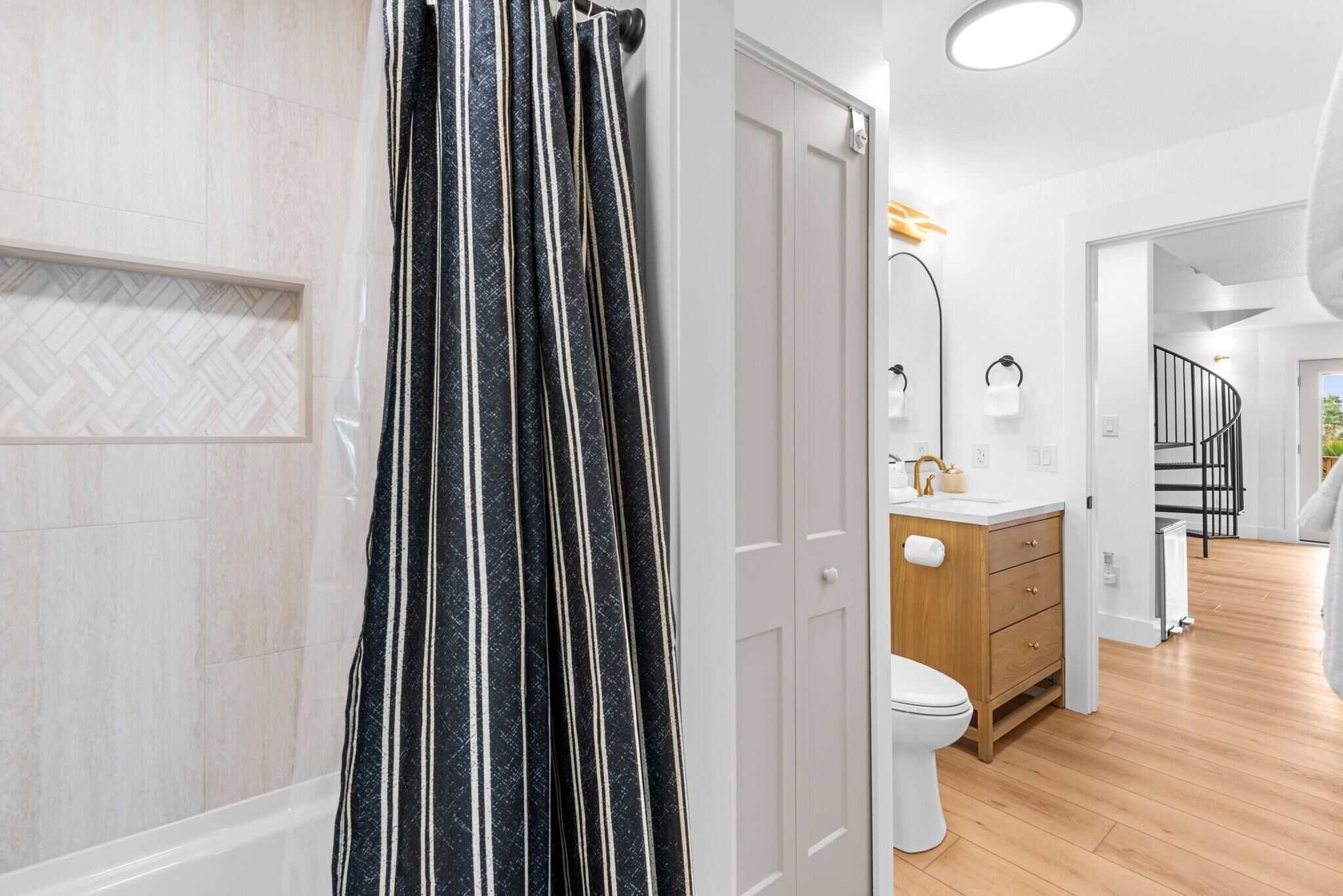 Ein modernes Badezimmer mit Duschvorhang, Toilette, Waschbecken und einem Holzkabinent.